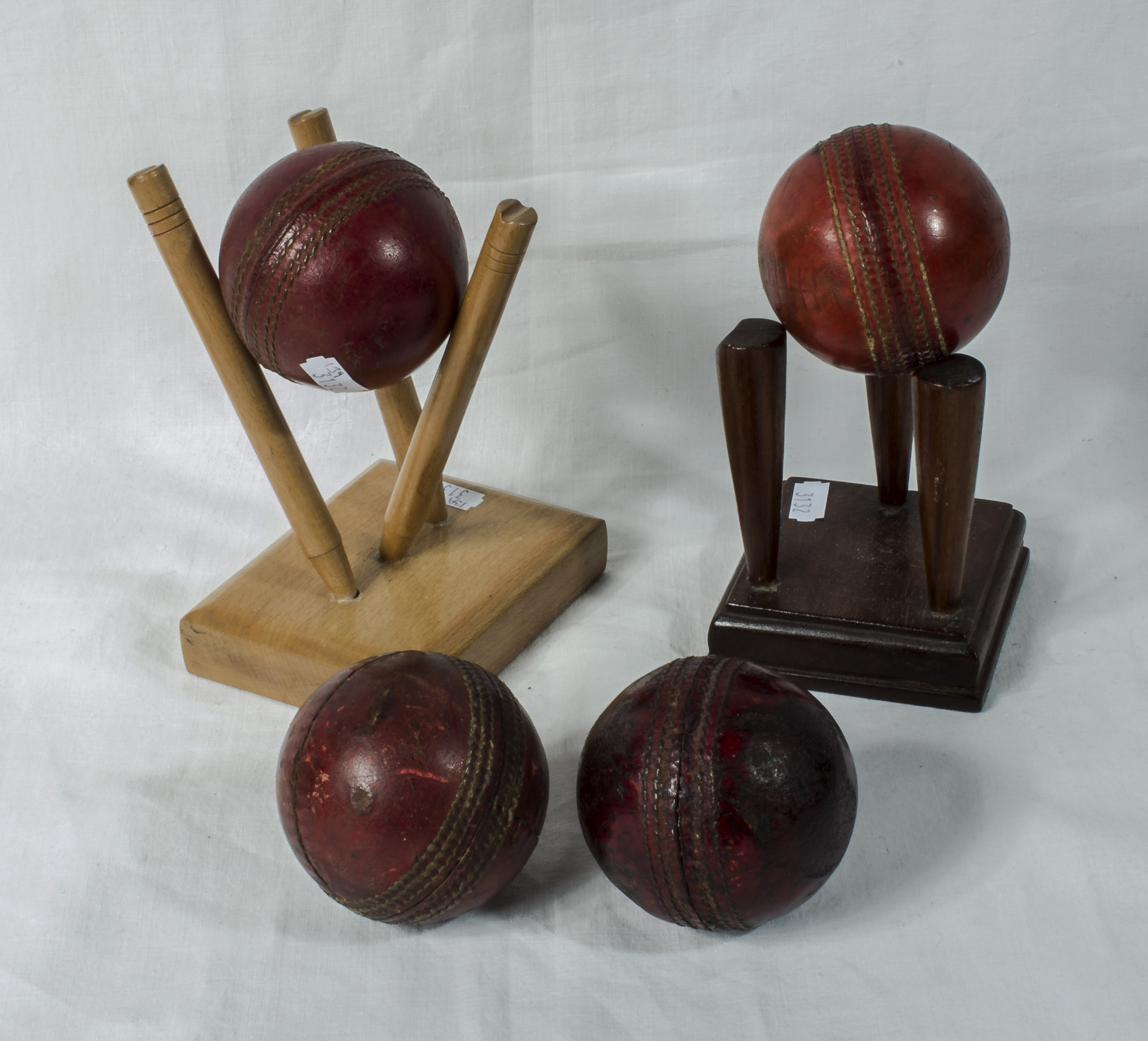 Four vintage cricket balls and two display stands