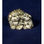 An ivory netsuke of a Shishi dog and pup, signed