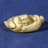 An ivory netsuke, man in a hammock, signed