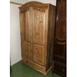 A pine two door wardrobe with drawer to the base