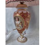 A 19th century cranberry glass table lamp having ornate gilt decoration with a painted depiction