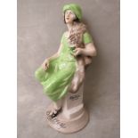 A rare Shelley china advertising figurine, circa 1930s of a woman seated in a green dress and hat