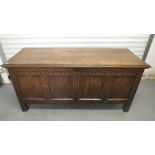 An 18th century George II oak blanket chest having a hinged lid over a panel front and block feet