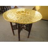 A Middle Eastern folding wooden table with brass tray top