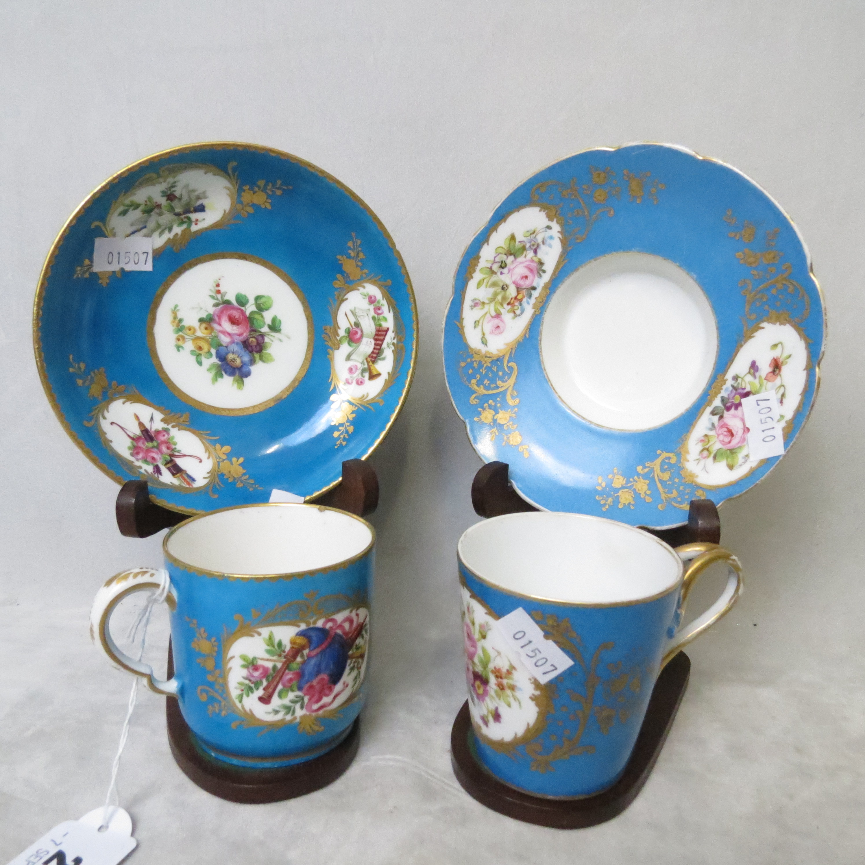 Two late 18th/early 19th century French, Sevres style cups and saucers with wooden display stands,