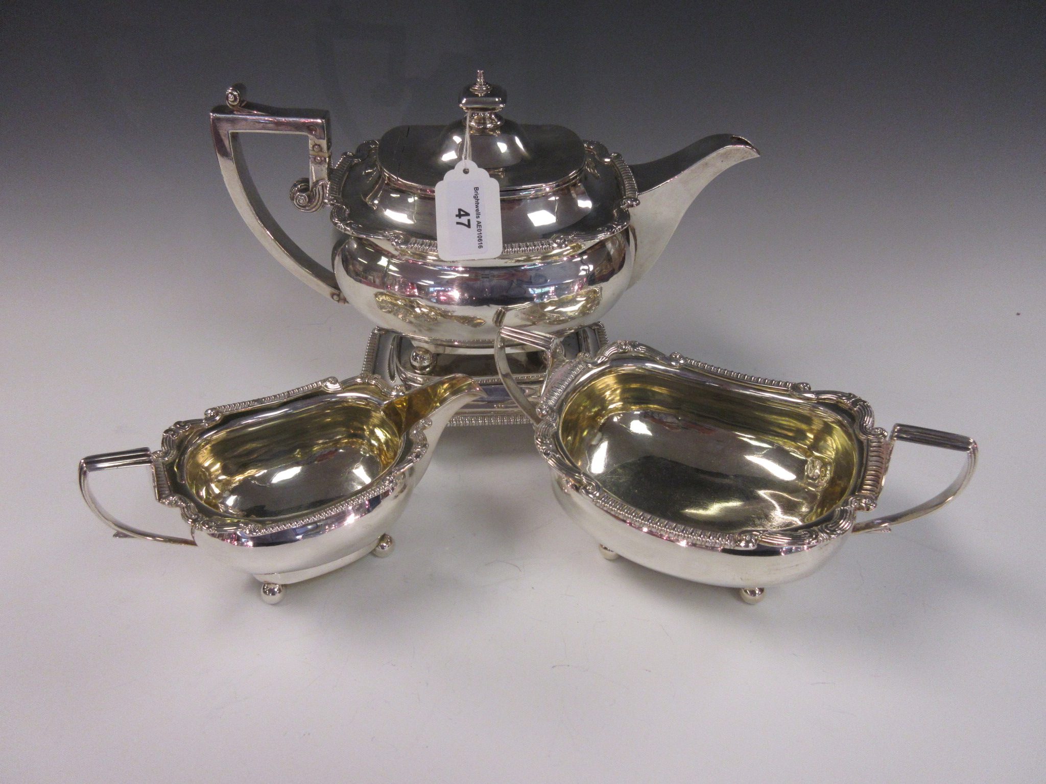 A George III silver boat shaped Teapot, Stand, Sugar Bowl, and Milk Jug with scroll borders,