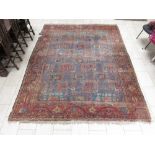 An old bordered Persian Carpet with red stylised motifs on a blue ground, principal border with