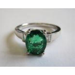 An Emerald and Diamond Ring claw-set oval-cut emerald, 1.46cts between two diamond baguettes in 18ct