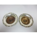 A pair of 19th Century Sheffield plated Coasters with floral scroll borders and turned wooden bases,