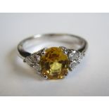 A Yellow Sapphire and Diamond Ring claw-set oval-cut yellow sapphire, 1.36cts, between trios of