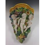 A Majolica Wall Sconce with three Putti climbing through leafage and floral encrusted foliage, 1ft