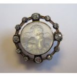 An Opalescent Glass and Diamond Brooch embossed cherub's head within halo frame set old-cut