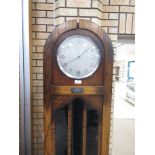 An Art Deco oak Longcase Clock with arched top, circular dial and weight chiming mechanism with