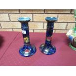 A pair of Rubens Ware pomegranate decorated Candlesticks with blue ground