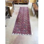 An Afgan Nahzat Runner with two rows of medallions on a deep red ground, 9ft 7in x 2ft 8in