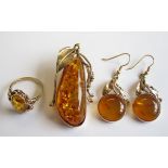 A modern Amber Brooch the irregular shaped stone set in intricate foliate mount together with