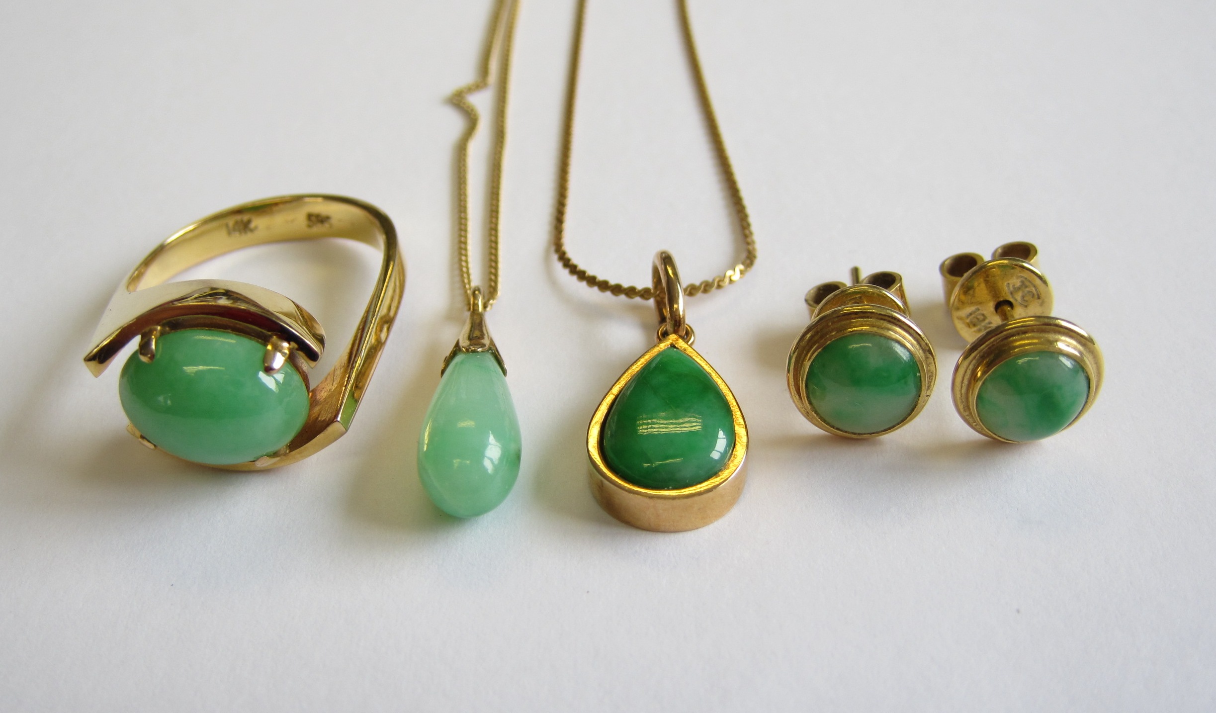 A Jade Ring claw-set oval cabochon in 14ct gold, ring size J, two Jade Drop Pendants on fine