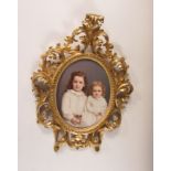 A German KPM porcelain oval Plaque painted two young girls, impressed mark in a carved decorative