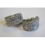 A pair of Diamond Earrings each with arc channel-set two rows of princess-cut stones in rounded