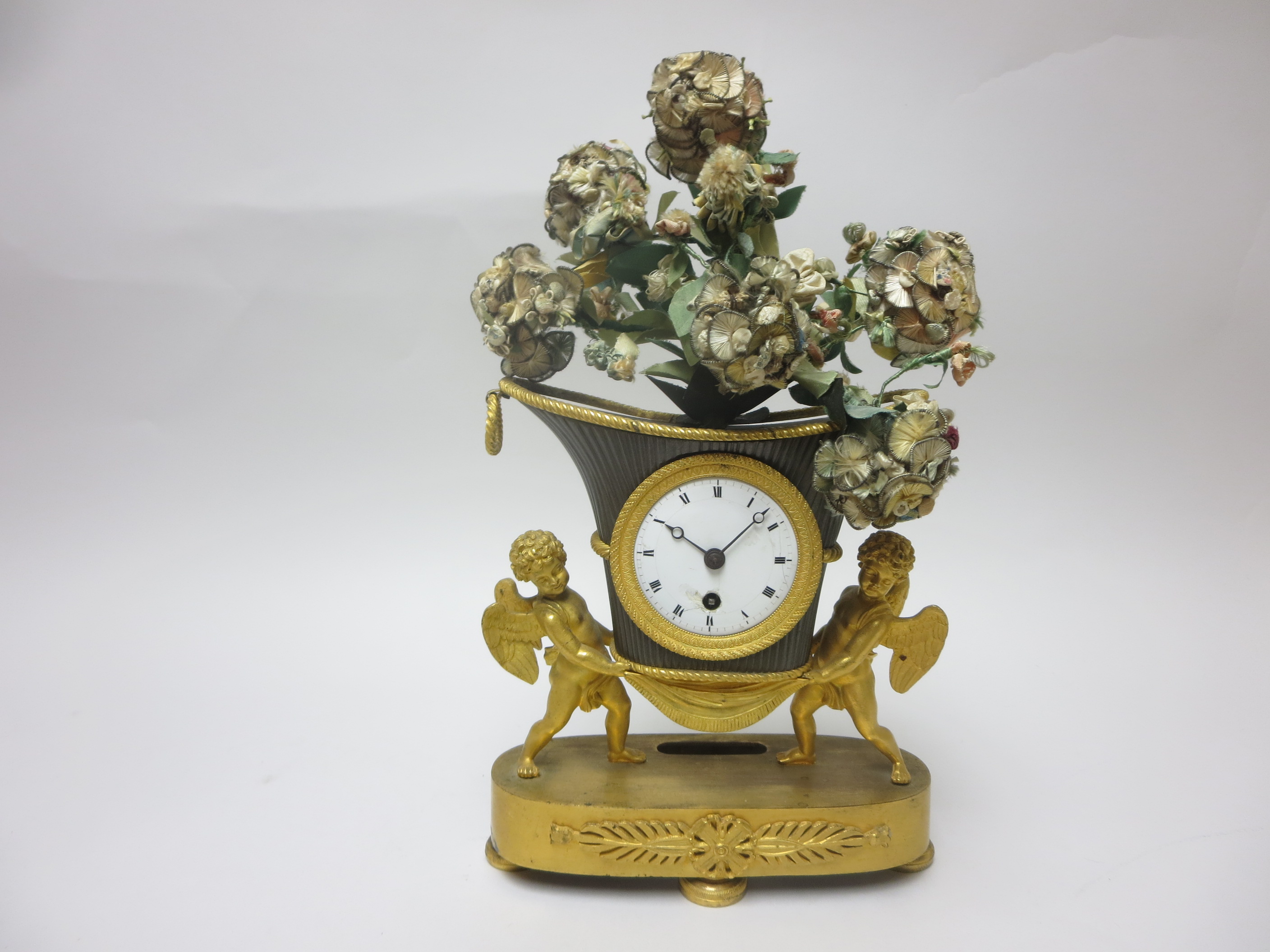 A 19th Century French Mantel Clock with white enamel dial in vase shape surround supported by two