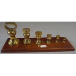 A Graduated Set of Six Brass Bell Weights and A Small Example on Wooden Plinth.