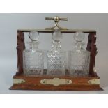 An Edwardian Oak Three Bottle Tantalus with Silver Plated Mounts.