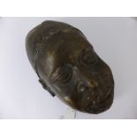 An African Bronze Mask of a Warrior, depicted wearing a pierced helmet, approx 32 cms