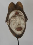 A Punu (West African) Mask, a feminine mask with elaborate coiffure ,white kaolin pigment to her