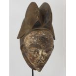 A Punu (West African) Mask, a feminine mask with elaborate coiffure, white kaolin face with full