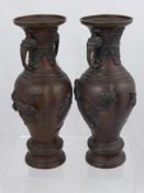 A Pair of Bronzed Vases, with decorative handles, the vase depicting birds in flight in relief,