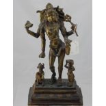 A Brass Indian Deity, depicted standing with a water bearer and sacred cow to either side of a lotus