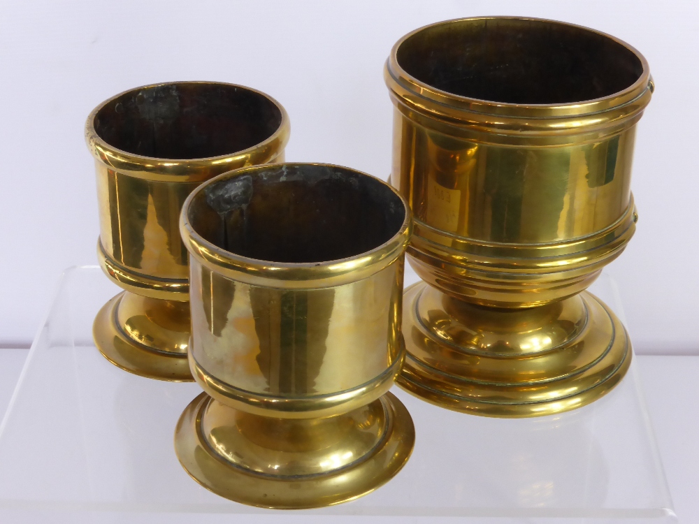 A Trio of Brass Graduated Candle Holders, together with a fireside copper kettle. (4)