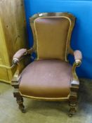 An Antique Easy Chair, with carving to the frame and handles, supported on turned legs and casters.