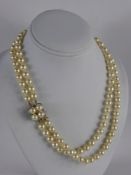 A Double Strand Pearl Necklace, the necklace having a yellow gold diamond and pearl clasp/pendant,