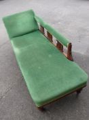 A Late Victorian Chaise Longue, with green buttoned upholstery, turned galleried back and legs.