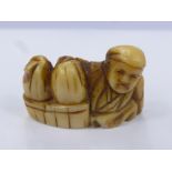 A Japanese Meiji Period Ivory Netsuke, the figure carved in the form of a merchant with baskets at