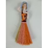 A Continental 1970's Porcelain Table Brush, in the form of a lady with fibre skirt.