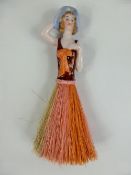 A Continental 1970's Porcelain Table Brush, in the form of a lady with fibre skirt.