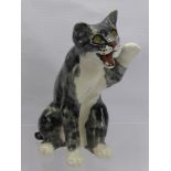 A Jenny Winstanley Porcelain Cat, seated with raised paw and glass eyes, approx 24 cms.