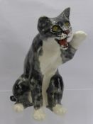 A Jenny Winstanley Porcelain Cat, seated with raised paw and glass eyes, approx 24 cms.