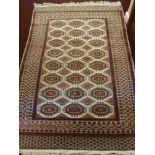 A Persian Style Carpet, with 24 central gul, with geometric border, claret design on cream ground,