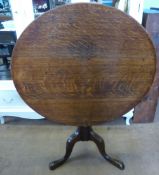 An Antique Oak Tilt Top Table, the table having a turned column on hoof feet, approx 89 x 76 cms.