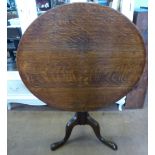 An Antique Oak Tilt Top Table, the table having a turned column on hoof feet, approx 89 x 76 cms.