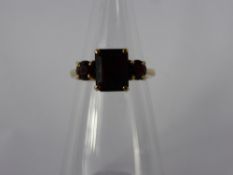 A 9 Ct Yellow Gold Garnet Ring. Centre stone 9 x 7 mm, 2 x 4.5 mm size P, approx wt 4 gms.