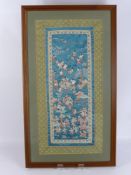 A Pair of Chinese Silk Embroidered Panels, depicting many figures in a landscape setting, framed and