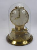 A Junghans ATO Brass Electric Clock, housed in a glass dome.