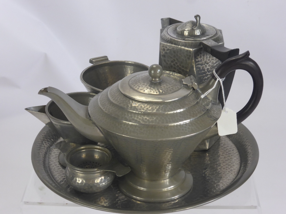 A Hammered Pewter Tea Set, in the Tudric style, comprising tea pot, sugar bowl, creamer, tea