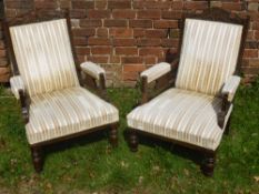 A Pair of Edwardian Arm Chairs, with swept arms, on turned legs and casters, decorative carving to