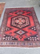 A Persian Woollen Carpet, of geometric design with floral outside border, jewel colours, approx