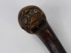 An Antique Walking Stick, the knop carved with an Oriental character with glass eyes and dice in his